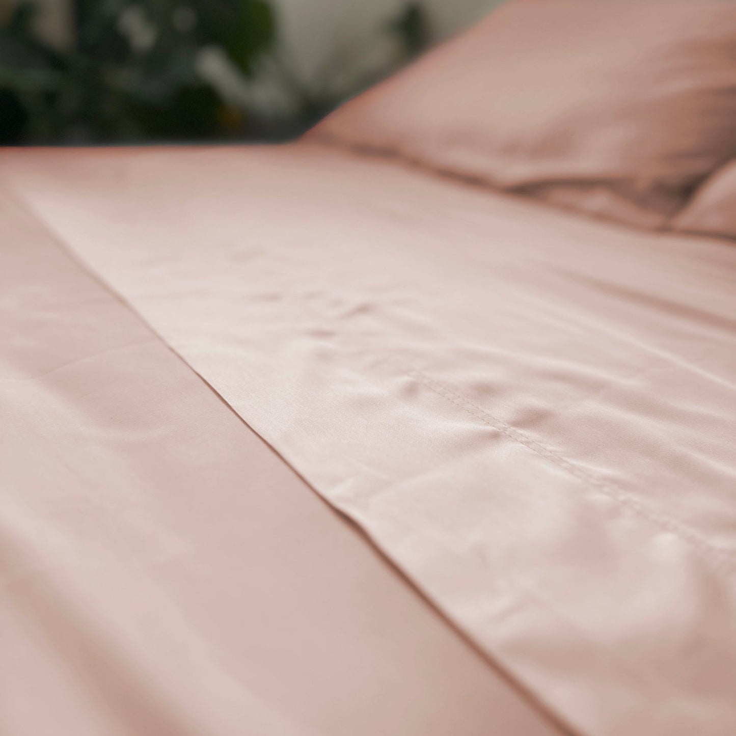Lençóis de bambu cor rosa em cama feita, com textura suave e acabamento acetinado, representando conforto e elegância — Momo Cotton