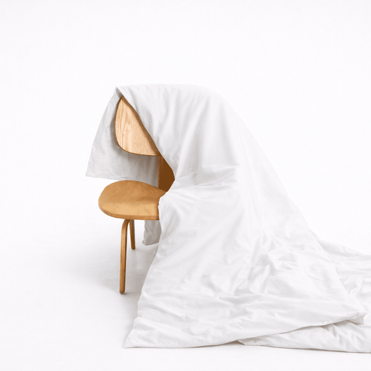 White bamboo duvet cover draped over wooden chair, showing soft fabric texture and hidden button closure design