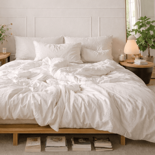 Jogo de cama em bambu branco exibido em cama com estrutura de madeira, almofadas e edredão em quarto claro