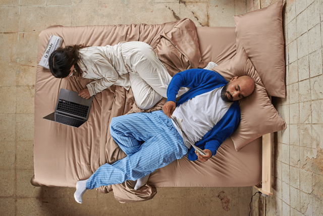 Couple in bed with bamboo sheets during the day, showing comfort across different seasons.