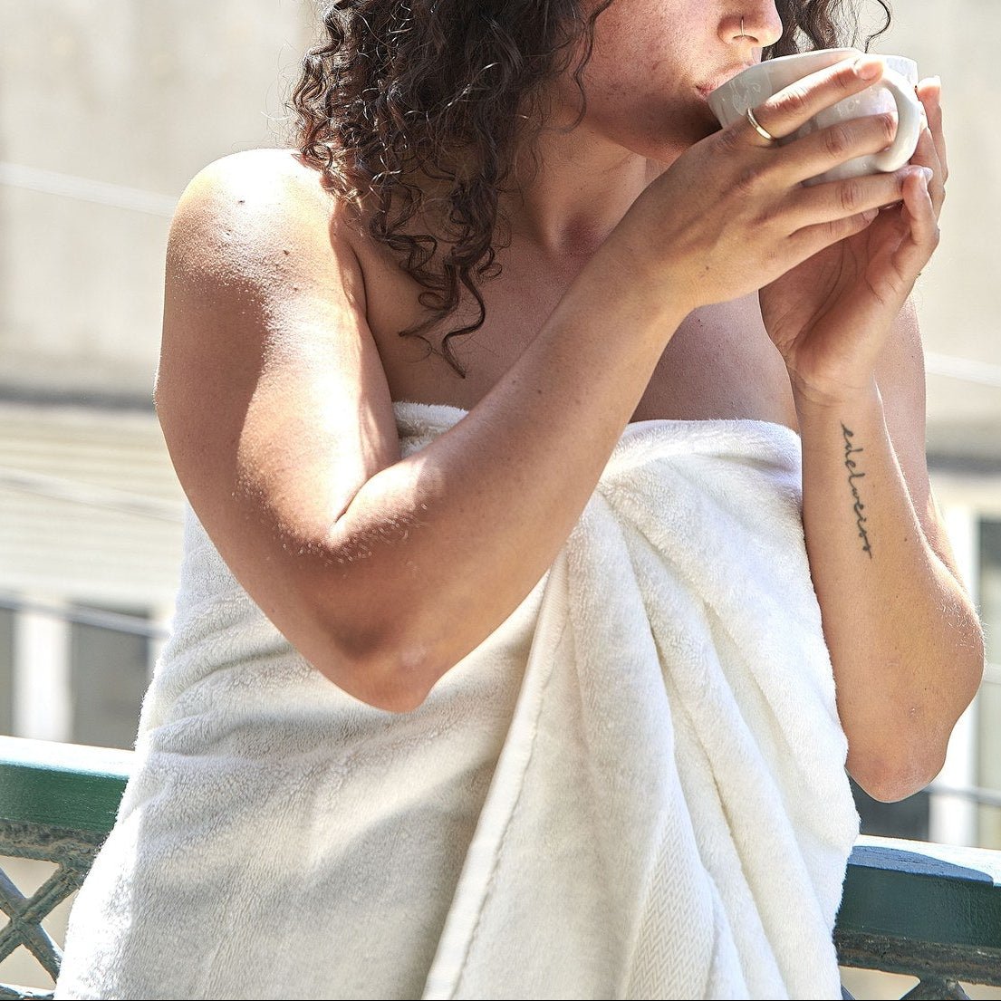 Woman holding white bamboo towel cup outdoors, showing soft texture and quality of Alba bamboo towel set