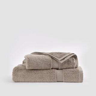 Beige bamboo towel set stacked, showing face cloth, hand towel, and bath towel against white background