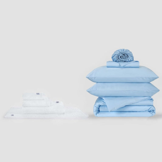 Blue and white bedding set with pillows and folded sheets displayed on white background