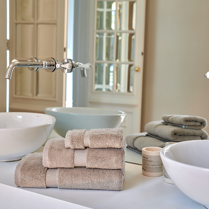 Alba bamboo towel set stacked on a modern bathroom sink in an elegant bathroom