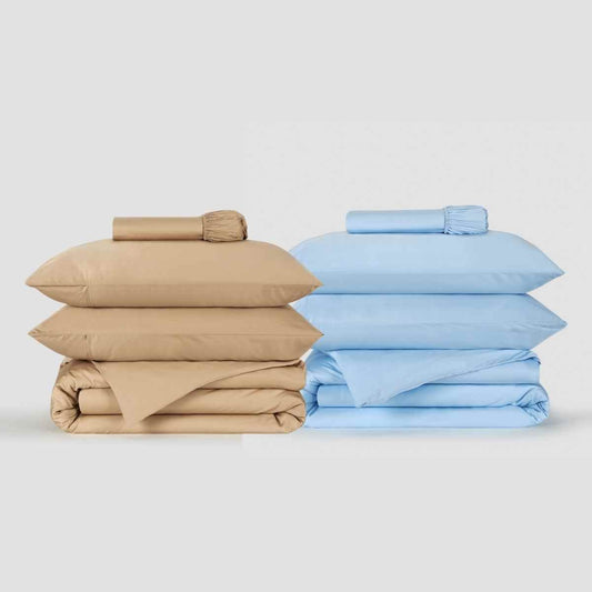 Beige and light blue duvet cover sets stacked and displayed with rolled sheets on white background