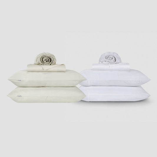 Two Jogo Lençol de Cima bedding sets in cream and white, stacked with pillows