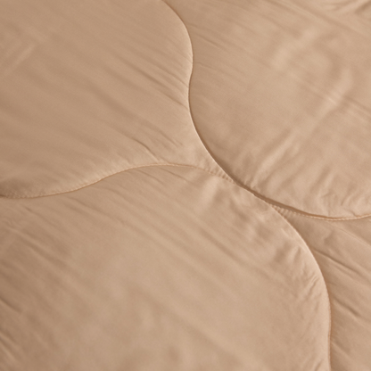 Edredão bege Momo Cotton em tonalidade neutra, vista de detalhe da textura acolchoada e costuras.